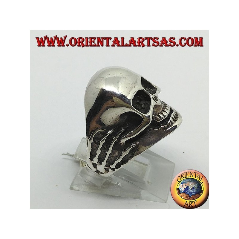Anillo en plata con calavera en las manos.