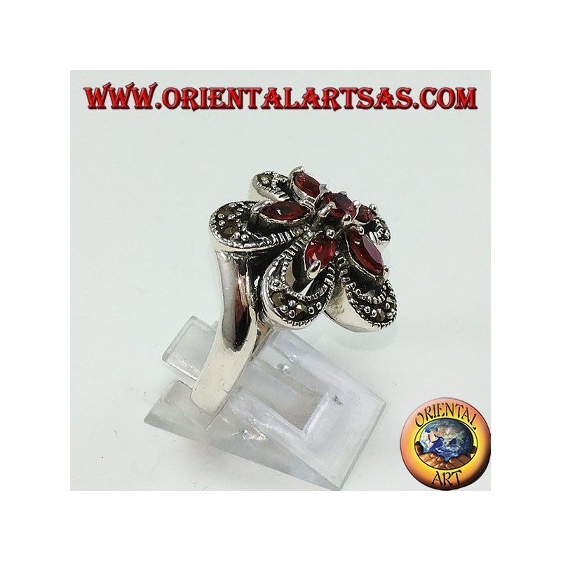 Anillo de plata con forma de flor con 5 granates lanzadera y una ronda central.