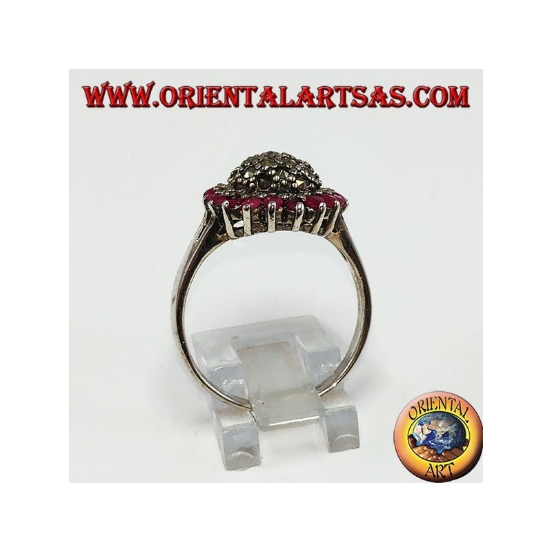 Anillo redondo de plata con un hemisferio de marcasita rodeado de 18 rubíes redondos.