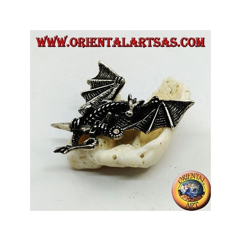 Pendentif dragon en argent avec ailes déployées et poignard entre les griffes