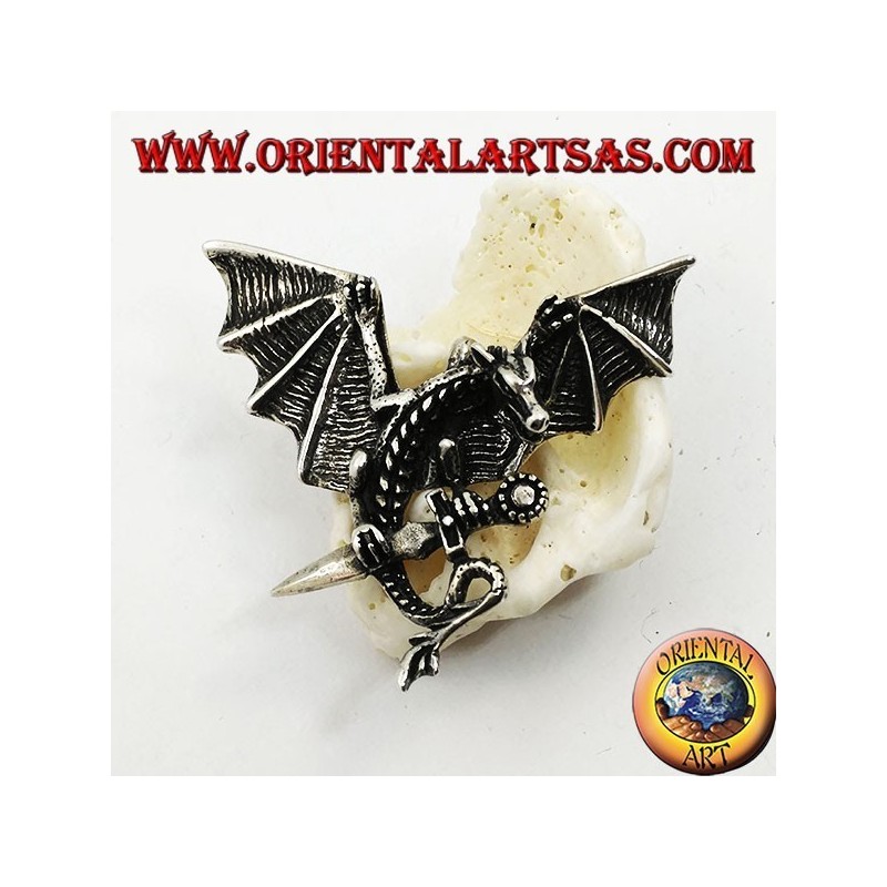 Pendentif dragon en argent avec ailes déployées et poignard entre les griffes