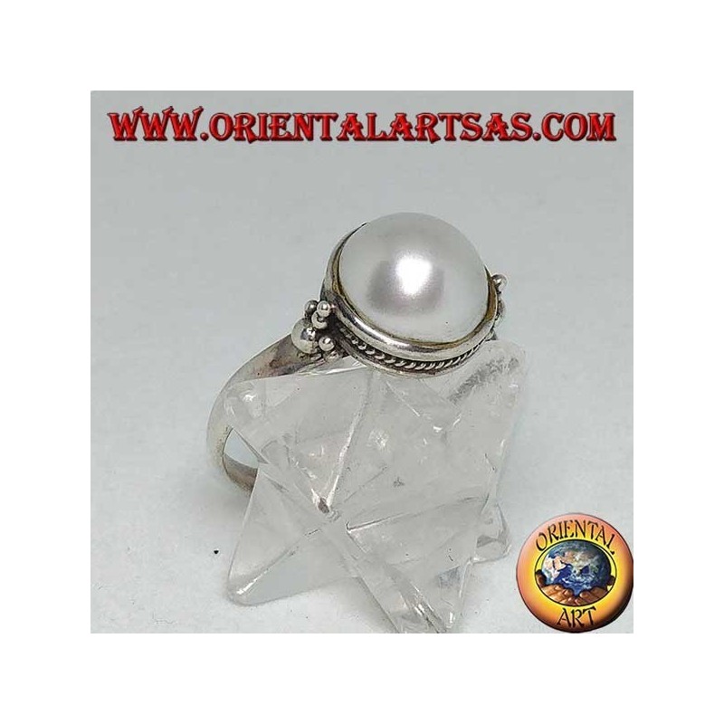 Silver ring with round pearl surrounded by braid decoration and balls on the sides