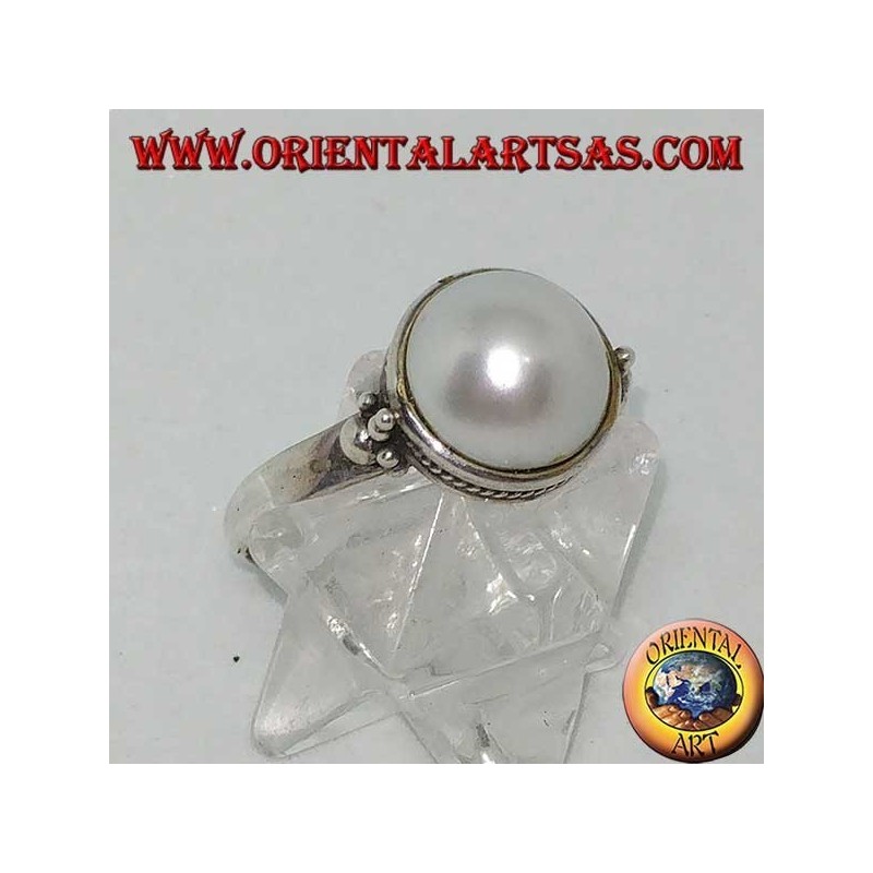 Anillo de plata con perla redonda rodeada de adornos trenzados y bolas a los lados.