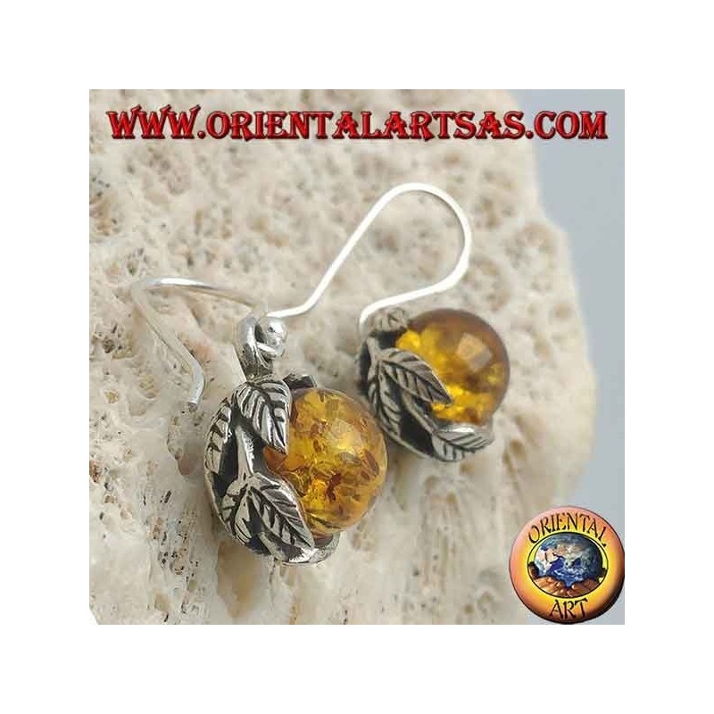 Pendientes de plata con esfera de ámbar natural entre las hojas.