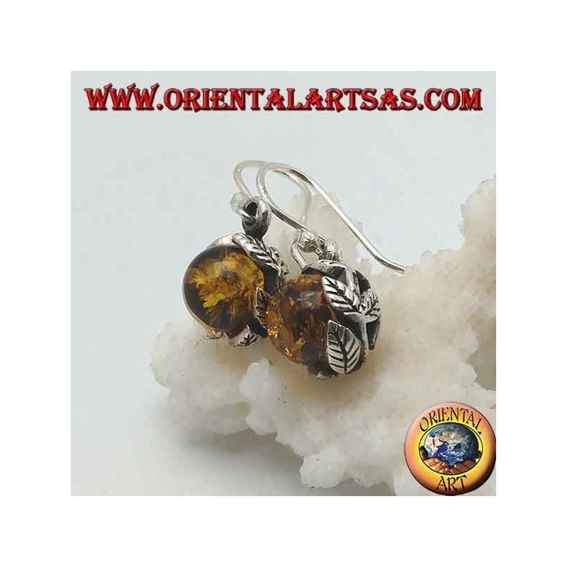 Boucles d'oreilles en argent avec sphère d'ambre naturelle entre les feuilles