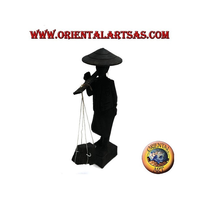 Escultura de un antiguo correo con sombrero de paja y palo con artículos de madera de ébano en el hombro.