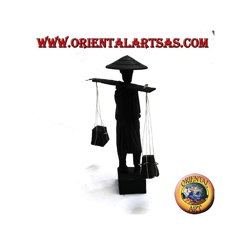 Sculpture of an ancient courier with straw hat and stick with ebony wood goods on the shoulder