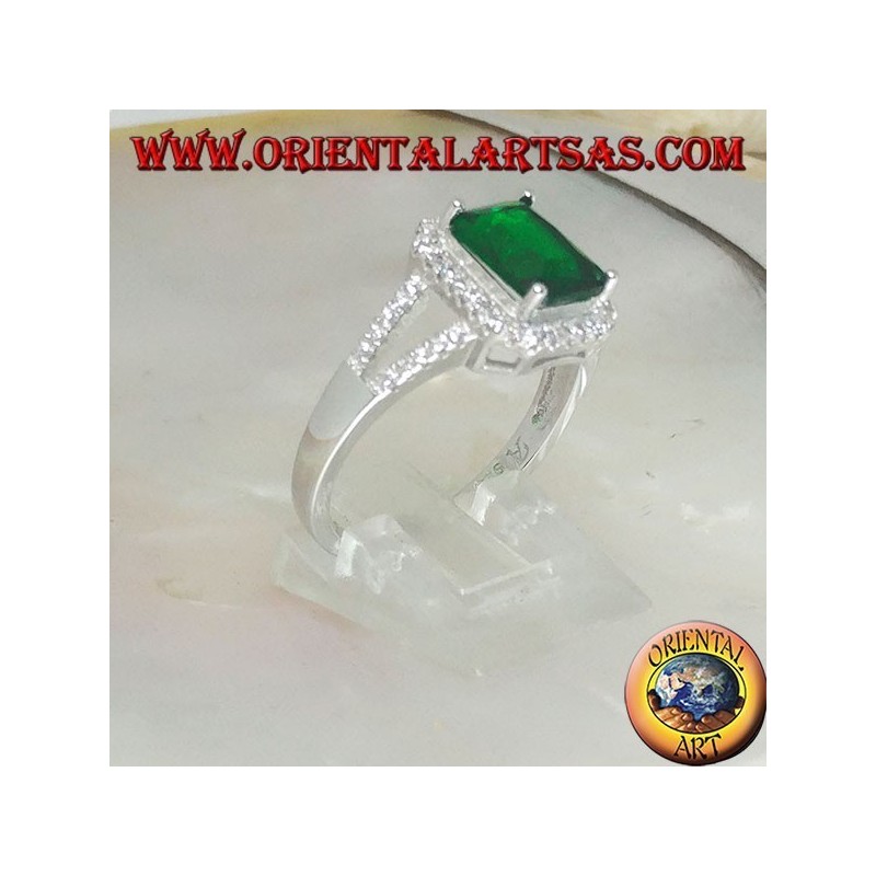 Anillo de plata con esmeralda sintética rectangular engastada rodeada de circonitas y dos líneas laterales.