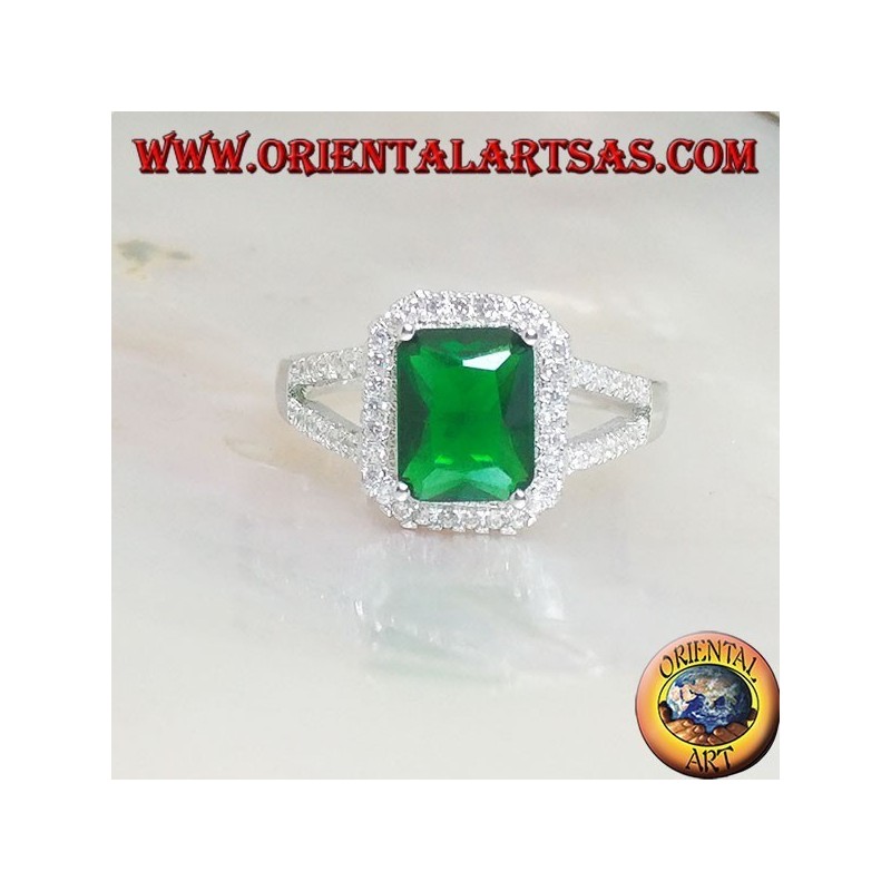 Anillo de plata con esmeralda sintética rectangular engastada rodeada de circonitas y dos líneas laterales.