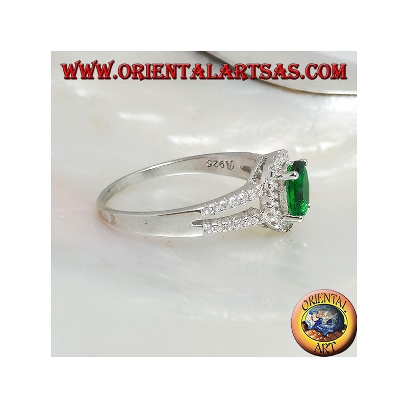 Anillo de plata con esmeralda ovalada sintética engastada rodeada de circonitas y dos líneas laterales.