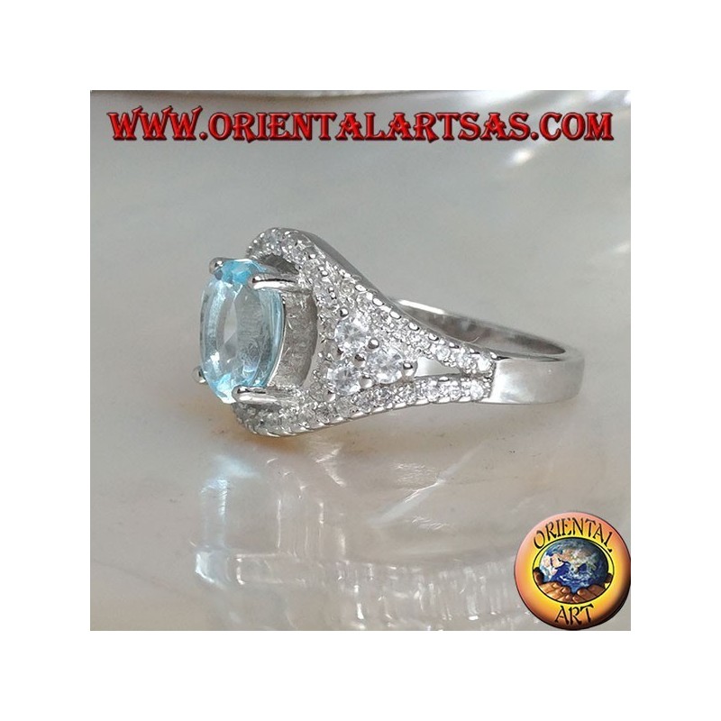 Anillo de plata con topacio azul natural ovalado en un marco con circonitas y tres rondas en los lados