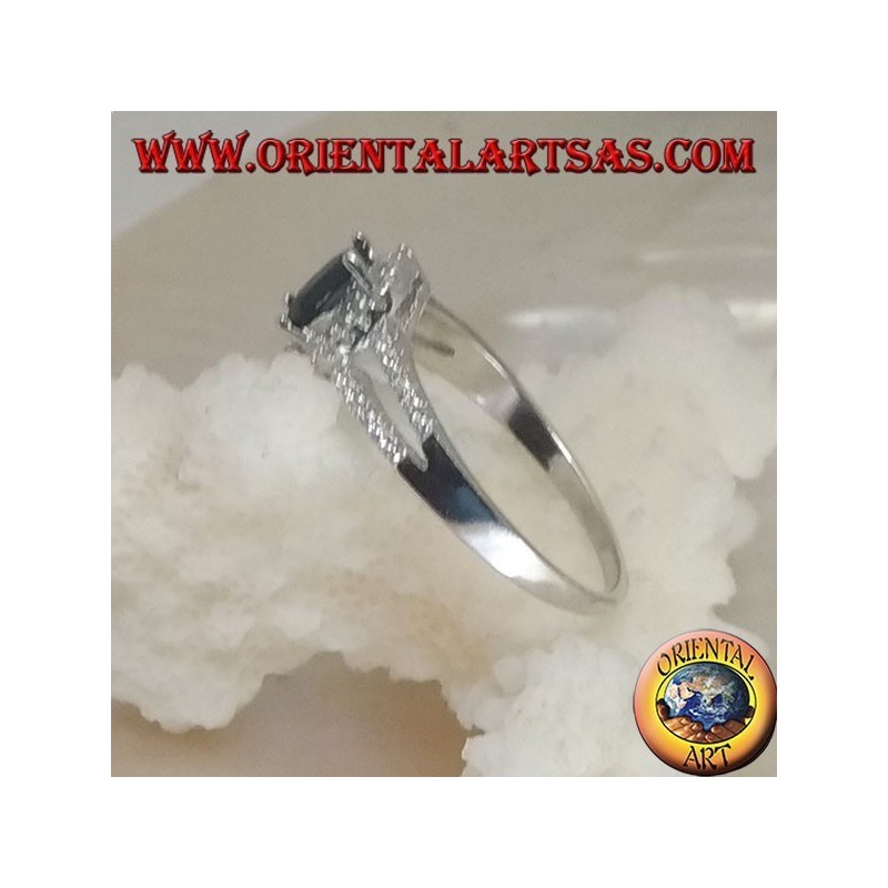 Anillo de plata con zafiro sintético ovalado, rodeado de circonitas y dos líneas laterales.