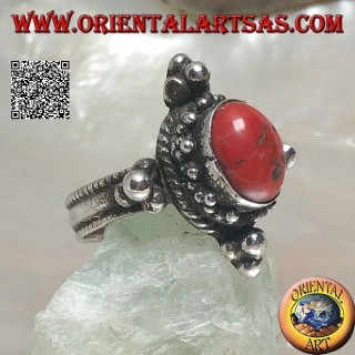 Anillo de plata con coral antiguo tibetano ovalado rodeado de puntos en un escenario nepalés