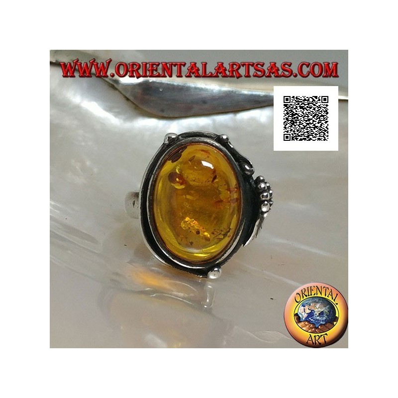 Silver ring with cabochon oval amber with two balls and a leaf on the edge