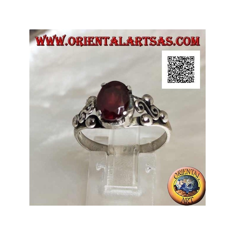 Silver ring with oval garnet set and spiral S between three balls on the sides