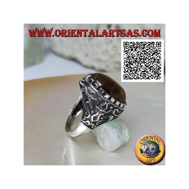 Anillo de plata con gran ojo de tigre ovalado de cabujón rodeado de decoraciones místicas en bajorrelieve