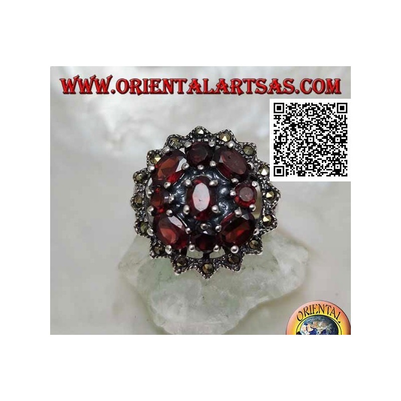 Anillo de plata con granate ovalado rodeado de granates redondos y ovalados en un sol de marcasita