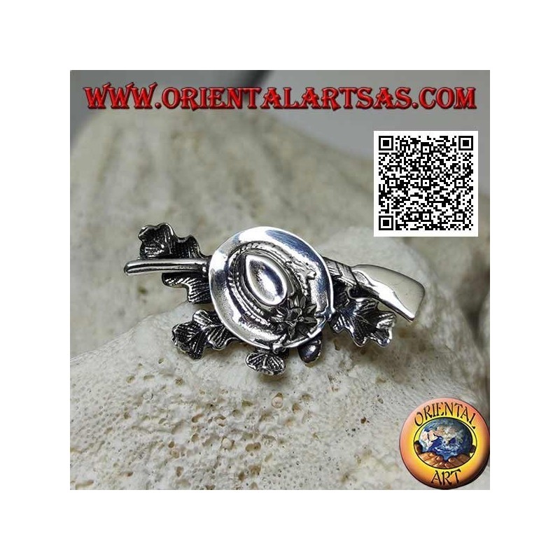 Broche de plata del cazador con sombrero y escopeta sobre alfombra de hiedra