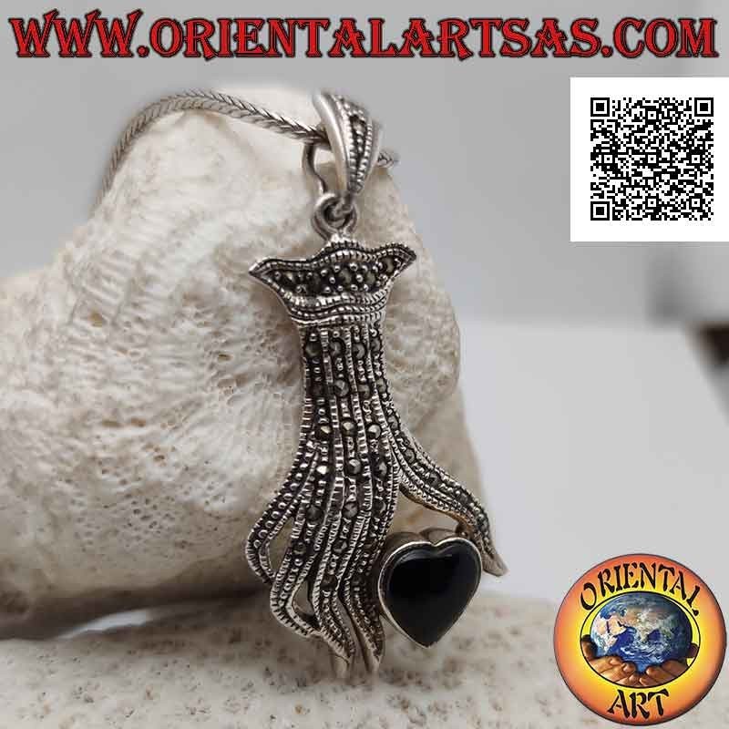 Colgante de plata, corazón de ónix entre los dedos de una mano tachonada de marcasita