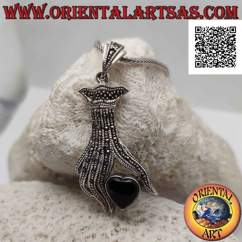 Colgante de plata, corazón de ónix entre los dedos de una mano tachonada de marcasita