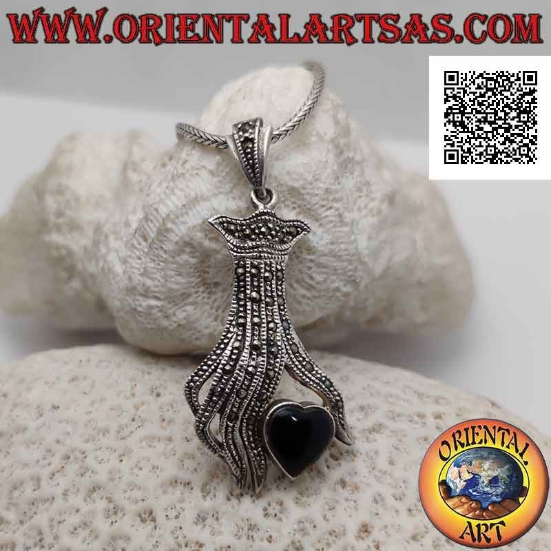 Colgante de plata, corazón de ónix entre los dedos de una mano tachonada de marcasita