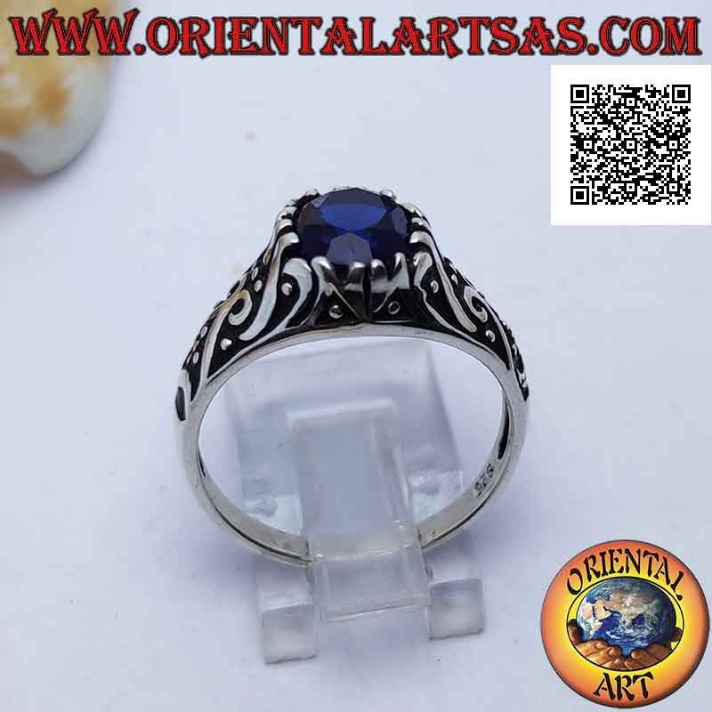 Silver ring with oval sapphire-colored zircon set on a frame decorated in bas-relief