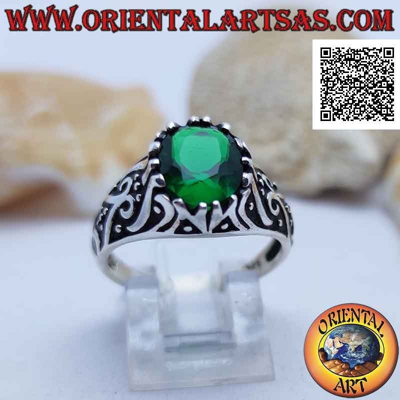 Silver ring with emerald-colored oval zircon set on a frame decorated in bas-relief