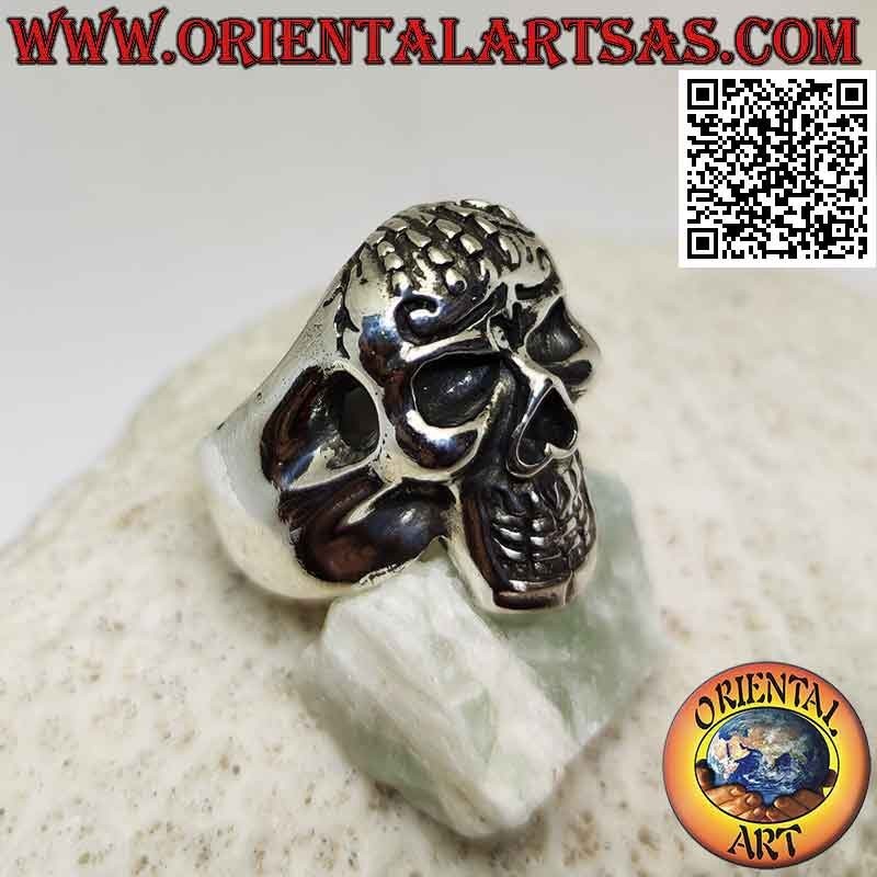 Anillo de plata en forma de calavera poseído con mano en la frente