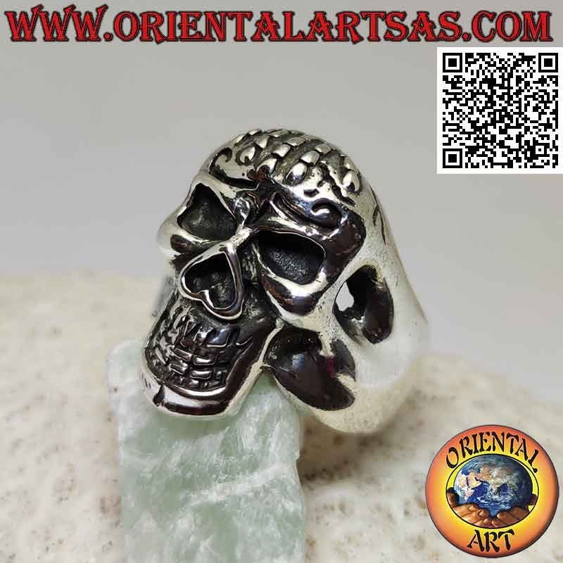 Anillo de plata en forma de calavera poseído con mano en la frente