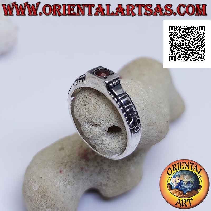 Silver ring with round garnet set in a raised square and checkered decoration