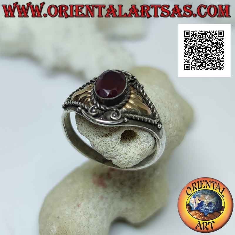 Ethnic style silver ring with oval cabochon garnet and 14 karat gold plates on the sides