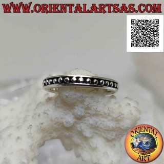 Anillo de plata con pequeñas esferas lisas sobre un fondo en bajorrelieve
