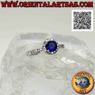 Anello in argento con zaffiro di sintesi tondo incastonato contornato da zirconi bianchi e sui lati
