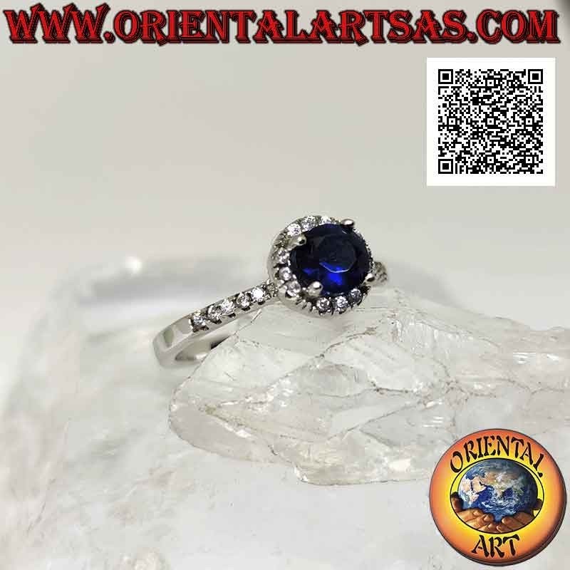 Anillo de plata con zafiro sintético redondo engastado rodeado de circonitas blancas y en los laterales