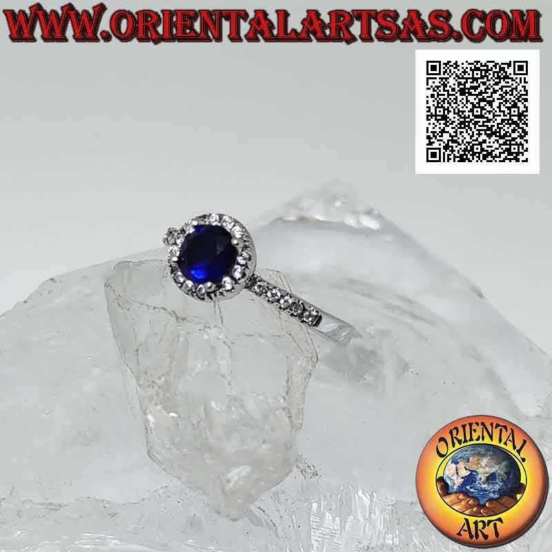Anillo de plata con zafiro sintético redondo engastado rodeado de circonitas blancas y en los laterales