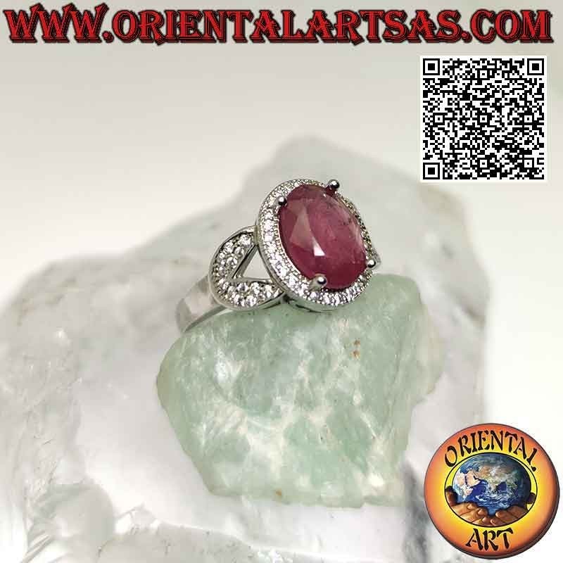 Silver ring with large oval natural ruby set surrounded by zircons and hooked on two sides