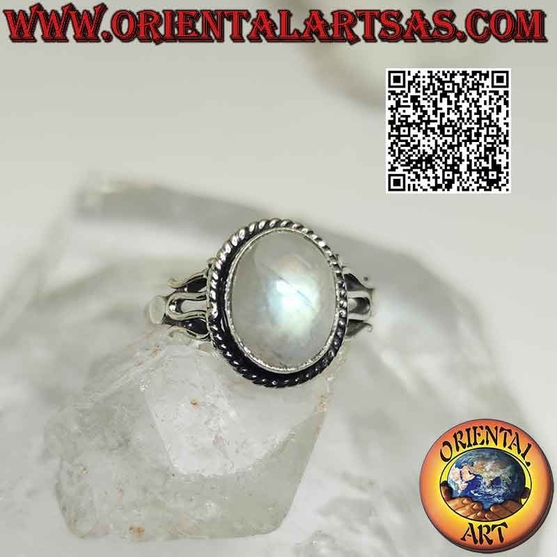 Silver ring with cabochon oval rainbow moonstone surrounded by interweaving and serpentine on the sides