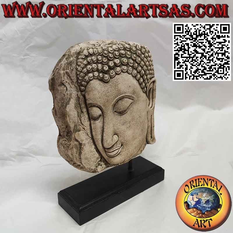 Steinskulptur eines Buddha-Gesichts im Profil mit Holzsockel