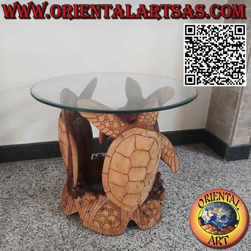 Mesa redonda con tres tortugas esculpidas y tapa de cristal tallado.