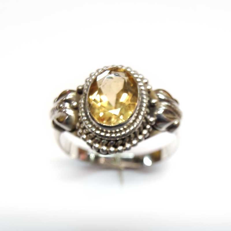 Bague en argent 925 ornée d'une topaze jaune ovale, d'un contour sphérique et de décorations latérales.