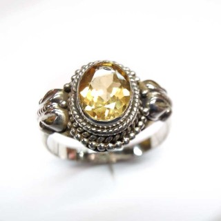 Bague en argent 925 ornée d'une topaze jaune ovale, d'un contour sphérique et de décorations latérales.